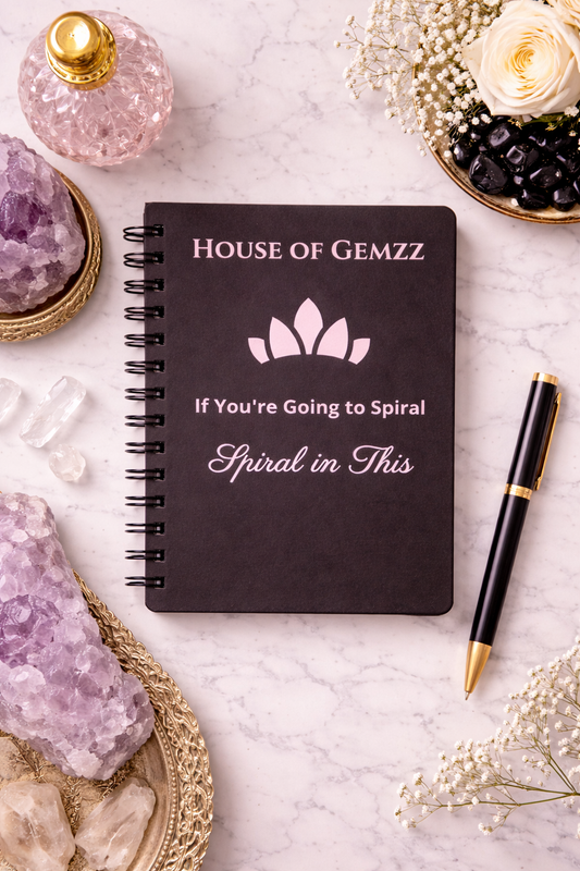 Black notebook with 'House of Gemzz' branding on a marble surface with crystals and flowers.