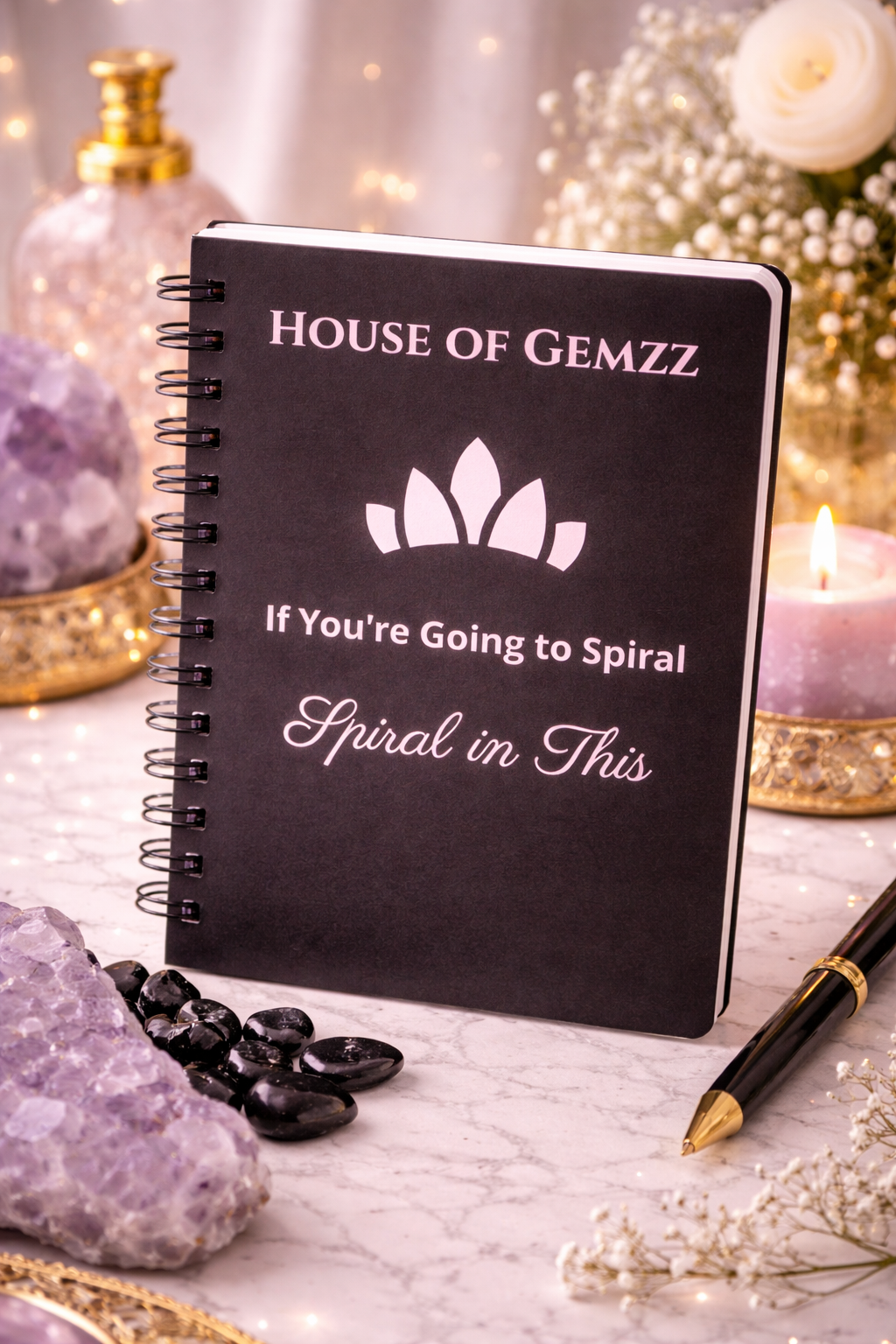 Black notebook with 'House of Gemzz' branding on a decorative surface with crystals and candles.