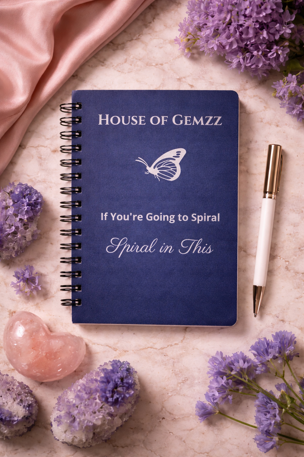Flat lay of navy spiral journal with silver butterfly design and pen, luxury journaling setup for manifestation and self-reflection by House of Gemzz