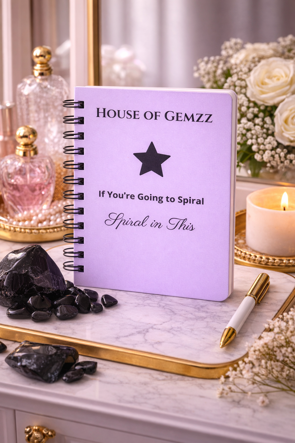 Lavender House of Gemzz journal with black star design styled with obsidian crystals, candle, and gold tray in luxury ritual scene