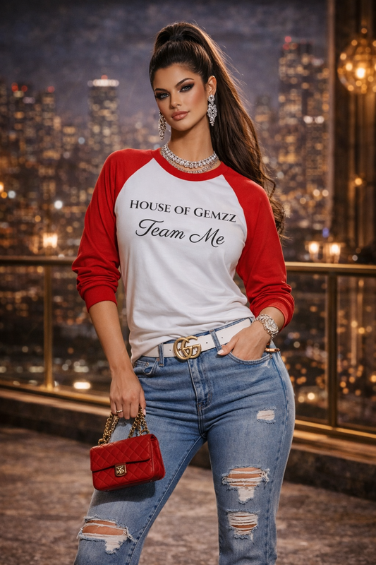Woman wearing a red and white 'House of Gemzz Team Me' shirt with ripped jeans in an urban setting.