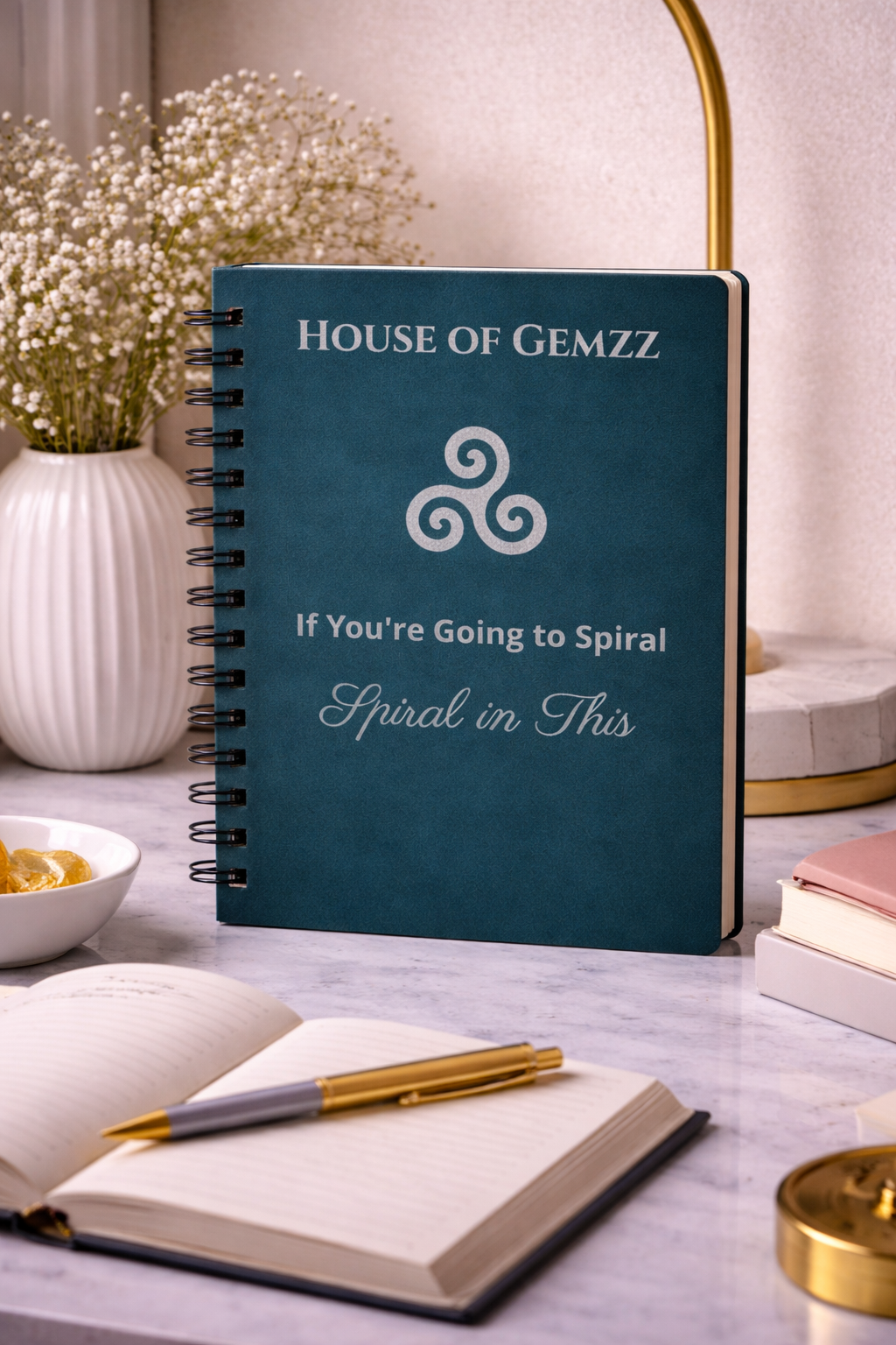 Blue notebook with 'House of Gemzz' branding on a table with decorative items.